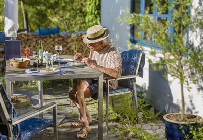 Senior man having meal at summer in front of house