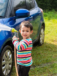 Portrait of cute boy washing car outdoors