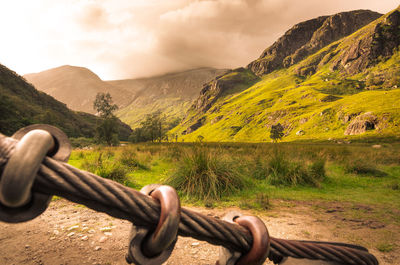 Fence on field by mountains against sky