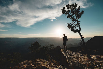 Silhouette man standing on rock against sky