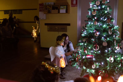 Rear view of women in illuminated christmas tree