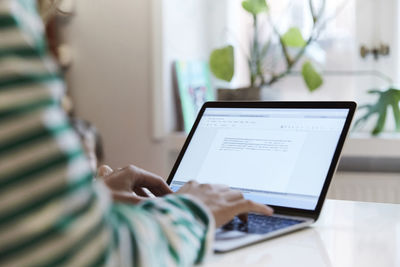 Cropped image of entrepreneur using laptop while sitting at home