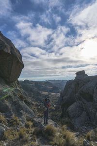 Man standing on rock against sky