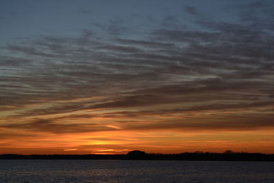 Scenic view of sea against dramatic sky during sunset