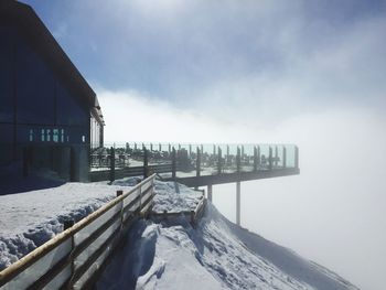 Built structure on snowcapped mountain against cloudy sky