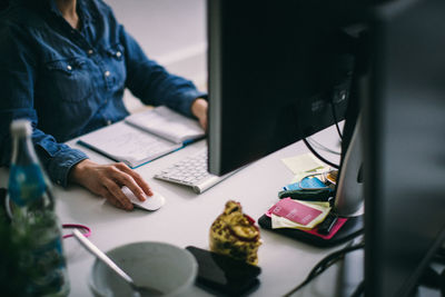 Midsection of businesswoman working at desk in office