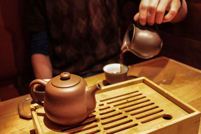 Midsection of man pouring tea cup on table