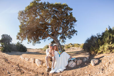 Woman sitting on tree trunk against clear sky