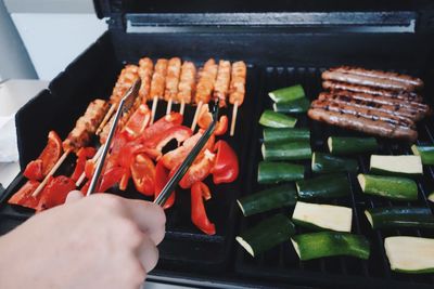 Close-up of person preparing food on barbecue grill