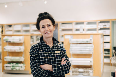 Portrait of smiling saleswoman with arms crossed standing in store