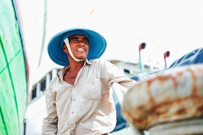 Portrait of man wearing hat standing against wall
