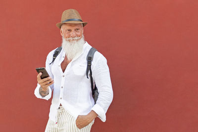 Midsection of man holding smart phone against red background