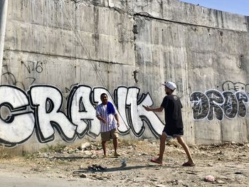 Friends standing against graffiti wall