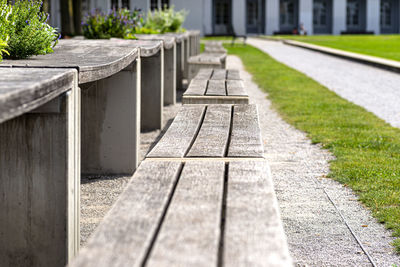 Benches and tables with flowers arranged in a row in the park, in the background a large building.