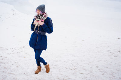 Full length of young woman photographing while standing on beach