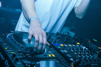 Midsection of man spinning decks  at underground rave