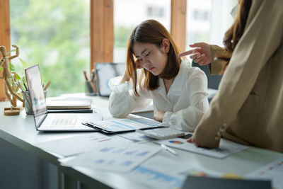 Worried female colleague looking at document in office