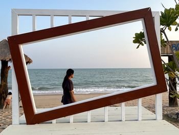 A girl is on the beach look at sea and standing after big frame 