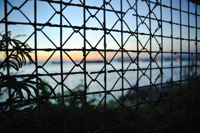 Full frame shot of chainlink fence against sky during sunset