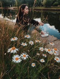 Woman sitting on the river beach among flowers