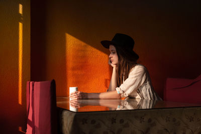 Portrait of young woman in hat sit alone in cafe