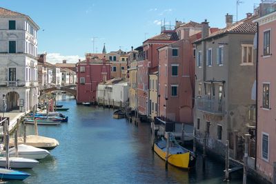 Boats moored in canal amidst buildings in city