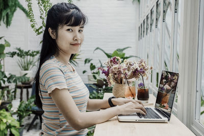Portrait of woman using mobile phone at table
