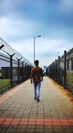 Full length rear view of man walking on footpath