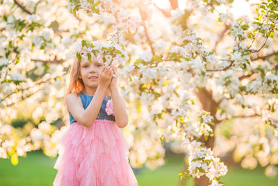 Full length of woman standing by flower tree