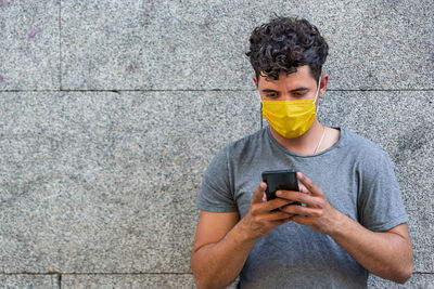 Young latin man with face mask using phone