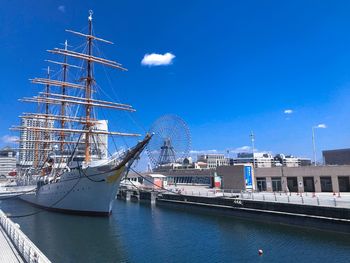 Sailboats moored at harbor against sky