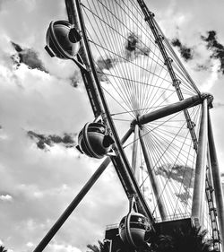 Low angle view of ferris wheel against cloudy sky