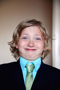 Close-up portrait of cheerful boy wearing suit standing at home
