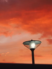 Low angle view of illuminated street light against orange sky