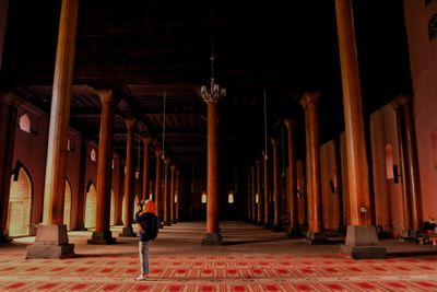 Rear view of man walking in illuminated building