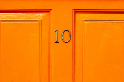 House number 10 on an orange wooden front door in london 