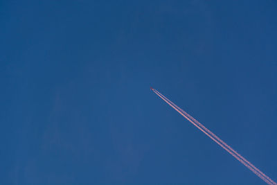 Low angle view of vapor trail against blue sky