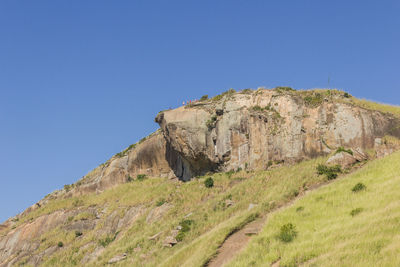 Low angle view of rock formation against clear blue sky