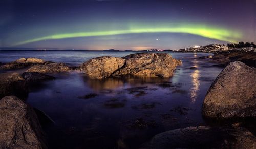 Scenic view of aurora borealis over sea at dusk