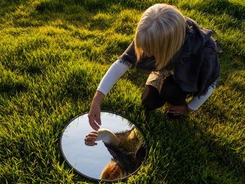 High angle view of woman with mirror on grass