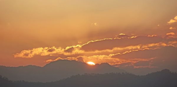 Scenic view of silhouette mountains against orange sky