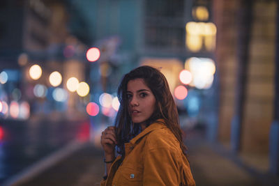 Side view portrait of young woman in illuminated city at night