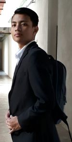 Side view of young man looking away against wall