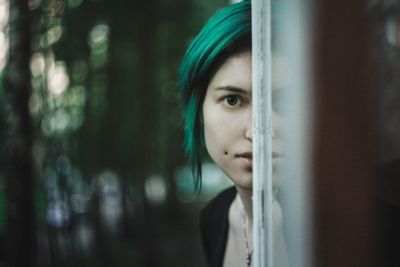 Cropped portrait of woman standing behind window