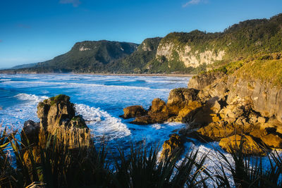 Scenic view of sea and rocks against blue sky