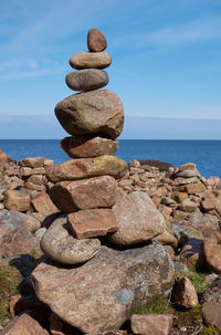 Stack of pebbles by sea against sky