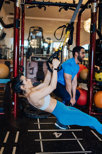 Side view portrait of young woman exercising in gym lifting 