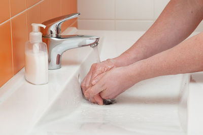 Close-up of person washing hands in sink