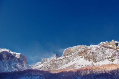 Scenic view of snowcapped mountains against blue sky