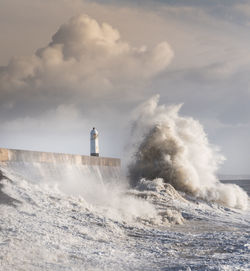 Lighthouse by sea against sky